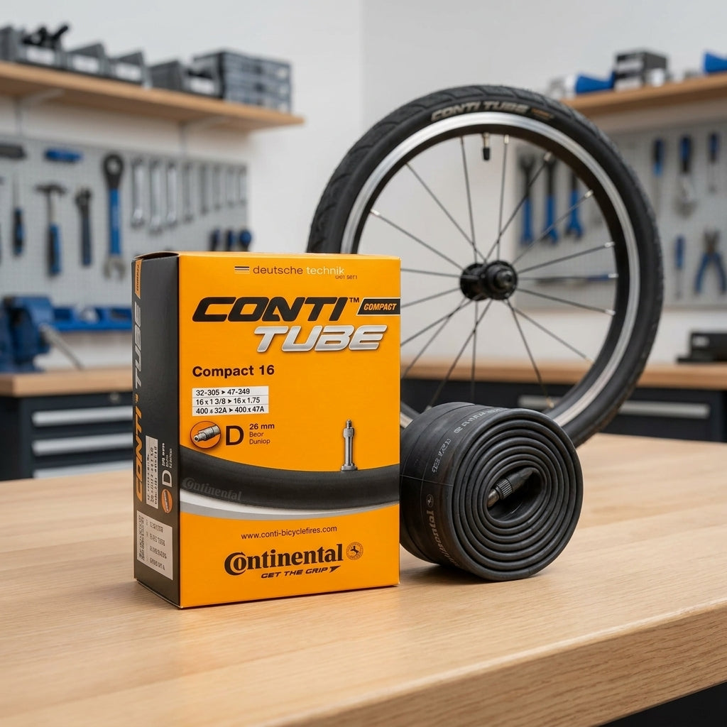 Continental Conti Compact 16 Fahrradschlauch 16 Zoll mit Dunlop Ventil, Box und Schlauchrolle auf Tisch.