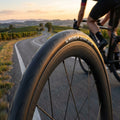 Michelin Dynamic Sport Drahtreifen 700x25 schwarz auf Carbonfelge, Rennradfahrer auf kurviger Straße.