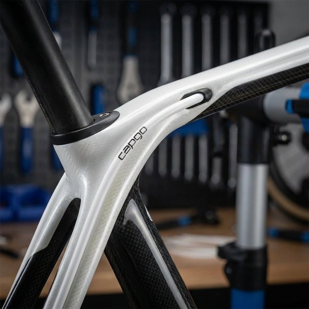Weiße capgo OL Schaltaußenhülle mit Kevlar und PTFE-Fett, am Carbon-Fahrradrahmen mit capgo Logo montiert.