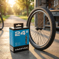 Impac Fahrradschlauch 24 Zoll mit Dunlop-Ventil 40mm in Verpackung neben Fahrradreifen und -felge im Freien.