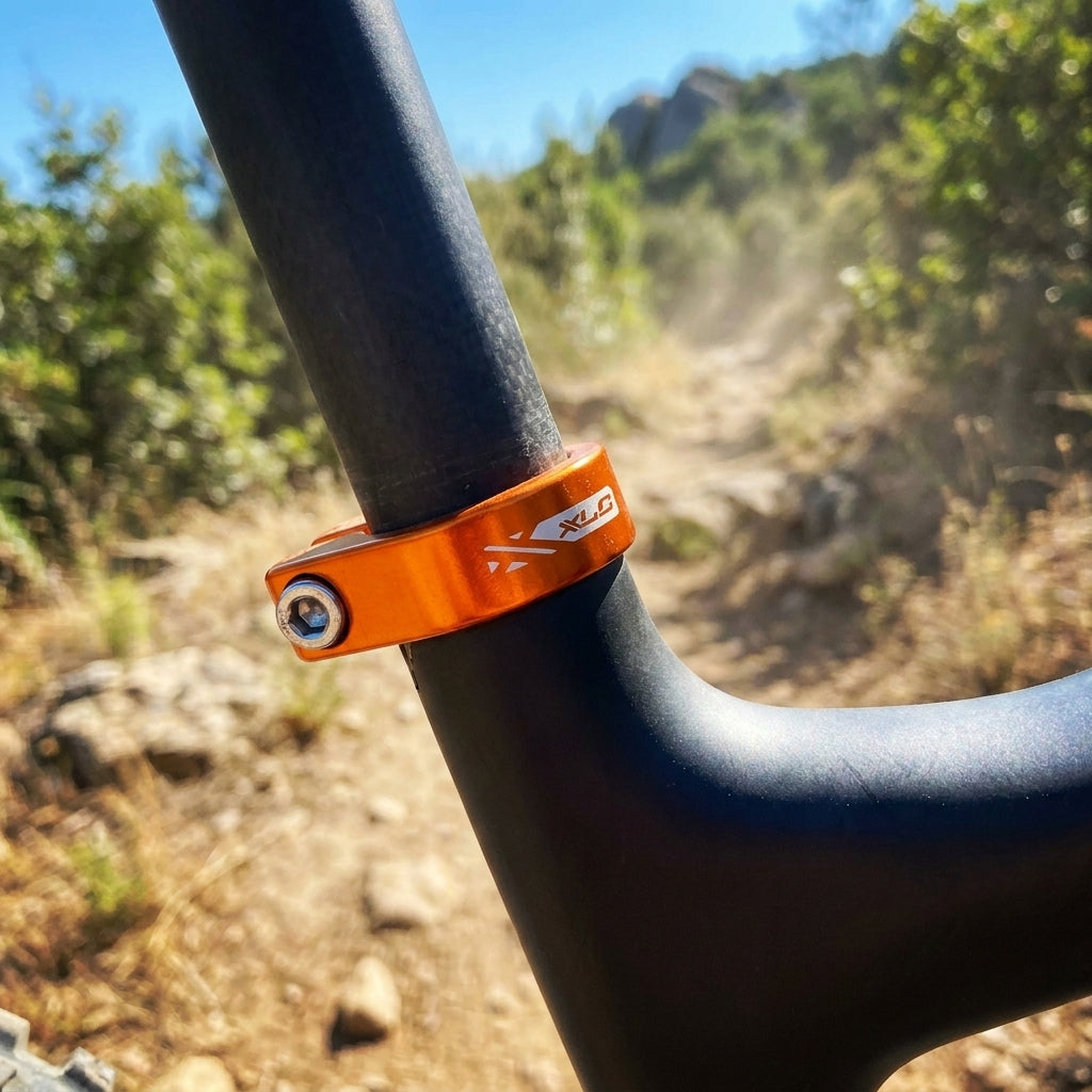 XLC Sattelstütz-Klemmring PC-B09 orange mit Innensechskant am Mountainbike auf staubigem Trail.