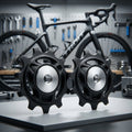 SHIMANO RD-R7100 Schaltrollensatz: Zwei schwarze Ersatzrollen für Schaltwerk, Rennrad im Hintergrund.