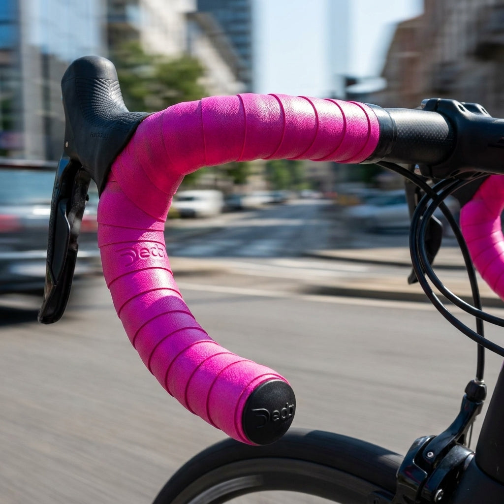 Deda Lenkerband fuchsia mit Stopfen am Fahrradlenker in Bewegung, Stadtkulisse.