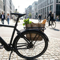 AtranVelo City Gepäckträger Alu schwarz mit AVS-System am Fahrrad, beladen mit Einkäufen in der Stadt.