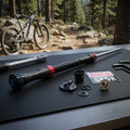 RockShox Pike Char2 RCT3 Dämpfer Upgrade Kit mit Einzelteilen und Werkzeug auf schwarzem Tisch. Mountainbike im Wald.