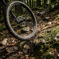 Robustes DT Swiss X1900 SPLINE 29" MTB-Laufrad schwarz spritzt Schlamm auf Waldtrail.