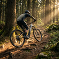 Haibike ALLTRAIL 10.5 29 E-MTB in schwarz/gold/grau auf sonnigem Waldtrail, Mountainbiker fährt.