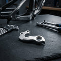 XLC Schaltauge DO-A28 Aluminium. Hochwertiges Fahrrad-Ersatzteil mit Werkzeug auf dunklem Untergrund.