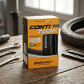 Continental Schlauch Compact 24 AV 40mm in offener Box auf Werkbank mit Fahrradreifen.