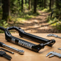 Glänzend schwarzes RockShox 35G Mountainbike-Federgabel-Unterteil mit Werkzeug auf Holztisch vor Waldpfad.