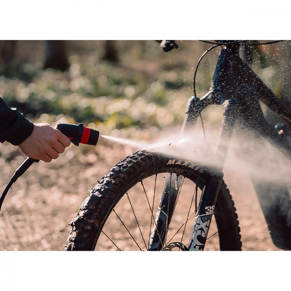 Bosch Fontus Akku Bike Cleaner reinigt dreckiges Mountainbike-Rad, Wasserstrahl entfernt Schmutz vom Reifen.