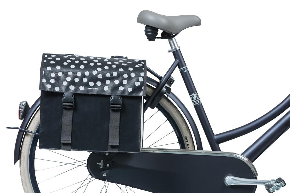 Wasserdichte Basil Urban Load DB Doppeltasche in Schwarz-Beige mit Punktmuster am Gepäckträger eines Fahrrads.