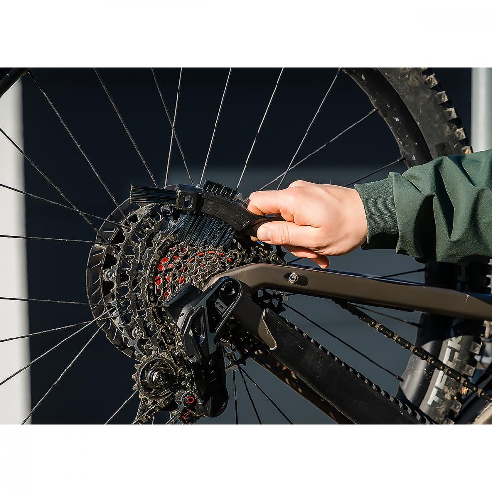 Hand reinigt Fahrradkette und Kassette mit Bürste. Zubehör für effiziente Fahrradpflege mit Bosch Fontus.