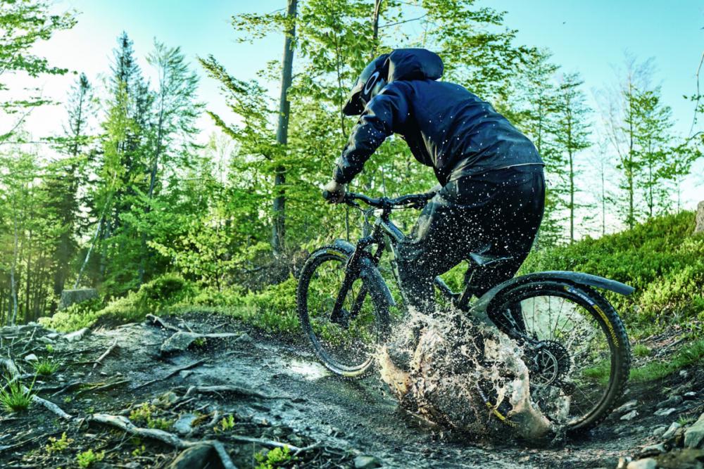 Mountainbiker mit SKS Mudrocker Hinterrad-Schutzblech fährt durch Schlamm, optimaler Spritzschutz für 27,5"-29" Räder.