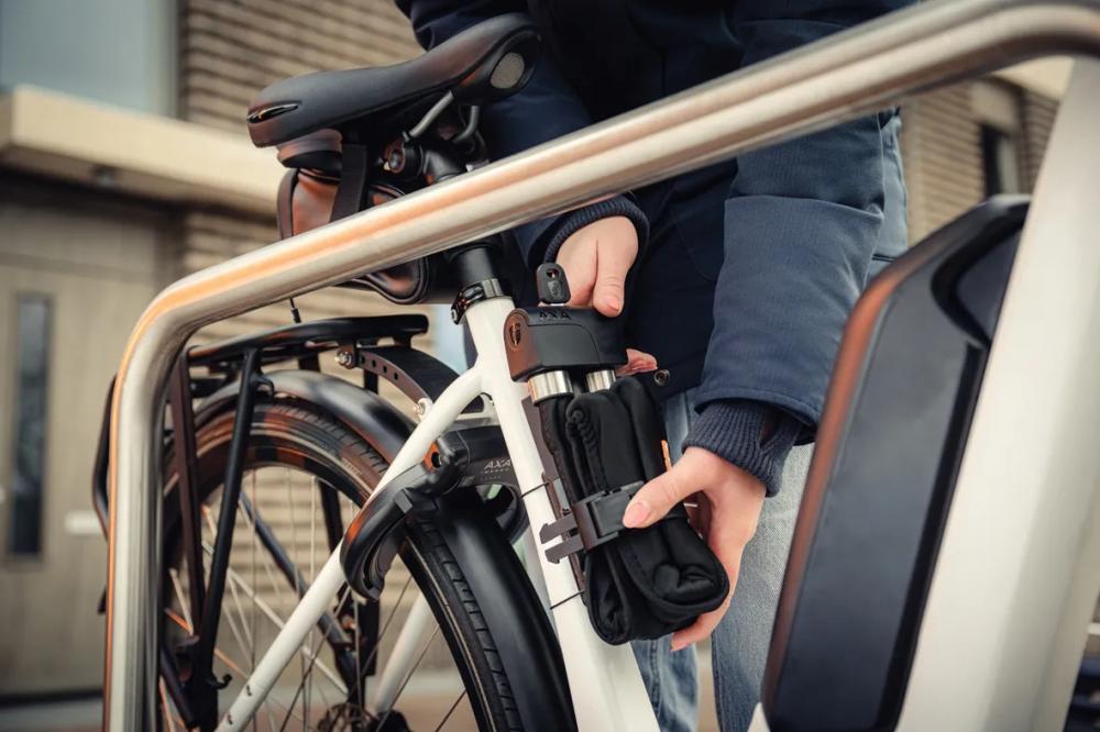 Person befestigt robustes AXA Faltschloss Foldable 8-100 mit hoher Sicherheit am Fahrrad.
