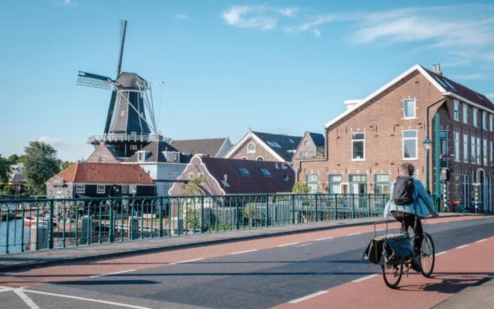 Selle Royal Alpine Athletic Sattel am Fahrrad eines Radfahrers auf Brücke, Windmühle im Hintergrund.