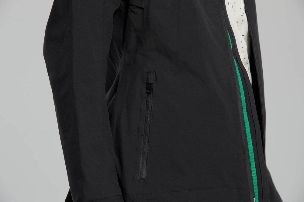 Schwarze Basil Skane Damen Regenjacke, Nahaufnahme mit Reißverschlusstasche und grünem Zierstreifen, wasserdicht.