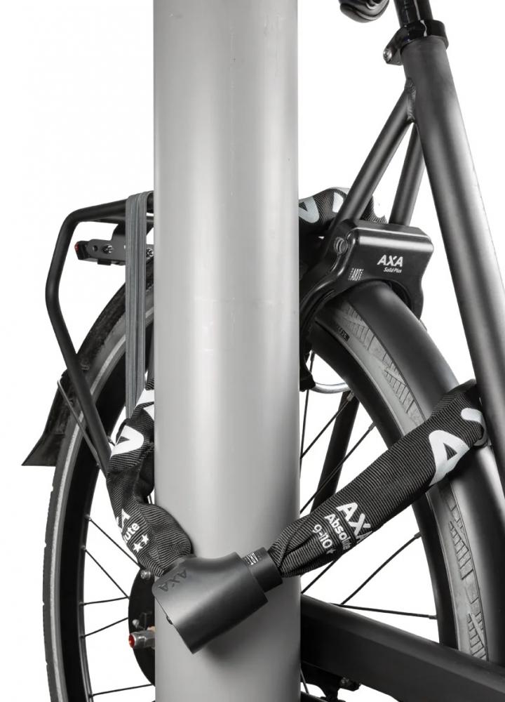 AXA Kettenschloss Absolute C5-90 Code 90 sichert ein schwarzes Fahrrad mit Zahlencode an einem Pfahl.