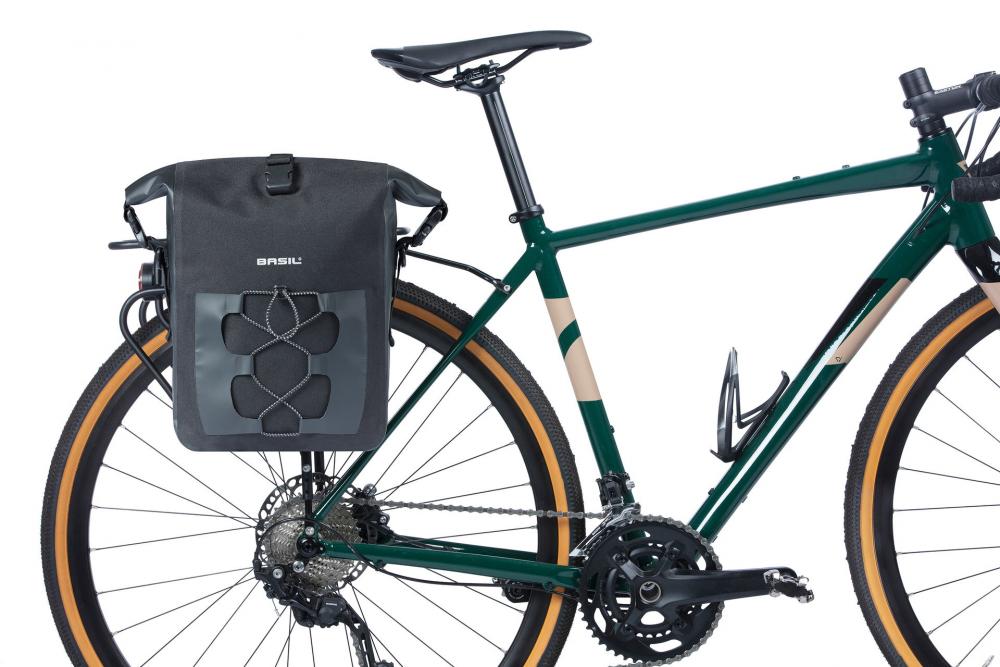 Schwarze Basil Navigator Waterproof M Einzelpacktasche am Gepäckträger eines grünen Fahrrads montiert.