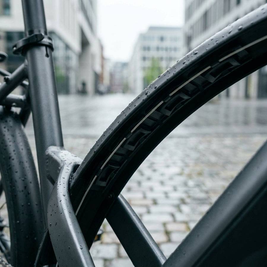 SKS MK Kabelführung am Schutzblech eines E-Bikes bei Regen auf Kopfsteinpflaster.