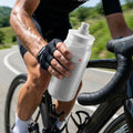 Radfahrer hält ultraleichte Elite Fly Tex 550ml Trinkflasche mit griffiger Oberfläche und Sportverschluss.