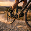 SHIMANO GRX FC-RX600 Kurbelgarnitur am Gravelbike in Aktion, Staub aufwirbelnd bei Sonnenuntergang.