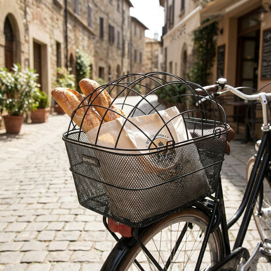 Schwarzer Basil Drahtgitter Fahrradkorb Pasja mit Baguettes am Rad in Gasse.