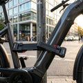 Trelock Faltschloss FS 480 TWIN sichert E-Bike an Laternenpfahl in der Stadt.
