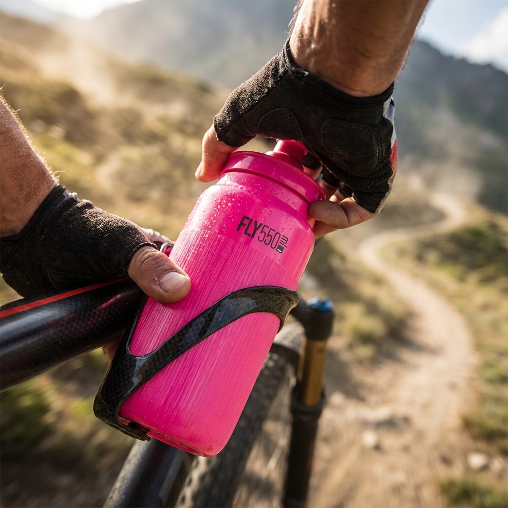 Ultraleichte ELITE Fly Tex Pink fluo 550ml Fahrrad-Trinkflasche am Mountainbike auf sonnigem Trail.