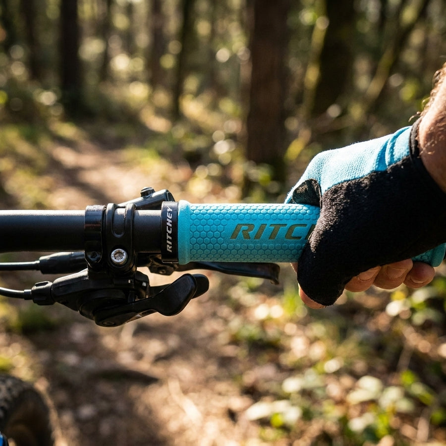 Himmelblauer Ritchey WCS Truegrip Fahrradgriff am Lenker, von Hand mit Handschuh gehalten, auf Waldweg.