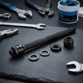 SHIMANO Hohlachse FH-M475-R Komplettkit Ersatzachse für Hinterradnabe mit Muttern, Scheiben und Werkzeug auf dunklem Grund.