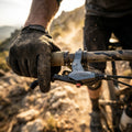 Avid Bremshebel Speed Dial 7 graphitgrau am Mountainbike-Lenker, von schmutzigem Handschuh gehalten.