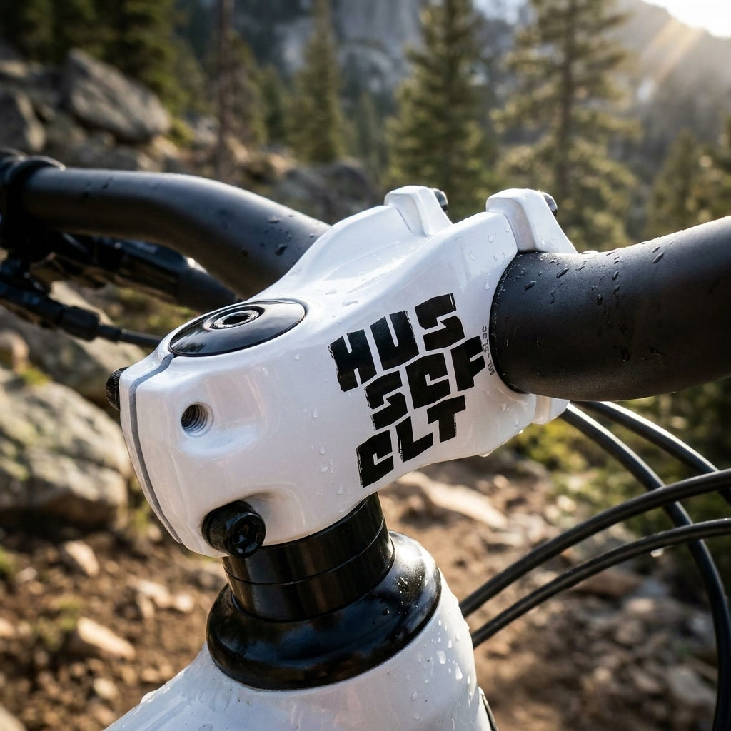 Truvativ Hussefelt Aluminium Vorbau in Schneeweiß am Mountainbike, nass von Wassertropfen, mit Berglandschaft im Hintergrund.