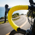 Deda Lenkerband gelb am Fahrrad auf sonniger Küstenstraße mit Meerblick.