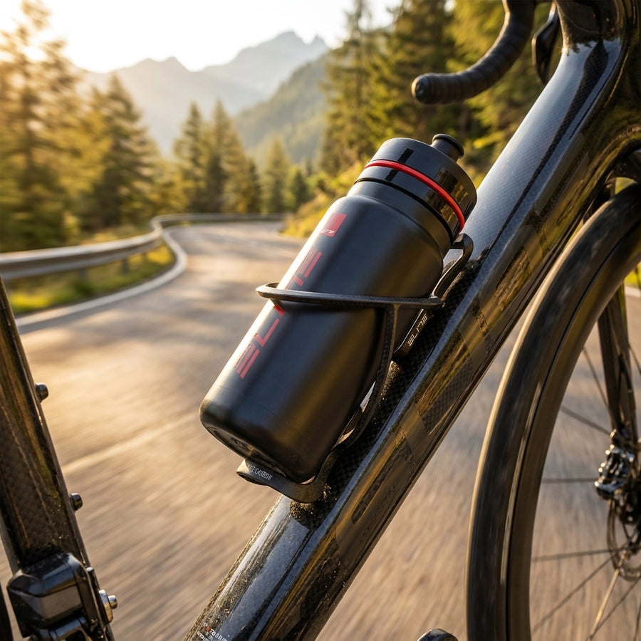 Schwarzer Elite T-Race Carbon Flaschenhalter mit Trinkflasche am Rennrad vor Berglandschaft.