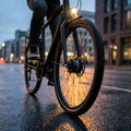 Fahrrad mit SHIMANO Dynamoeinheit 108 mm DH-3D37-QR Schwarz am Vorderrad, beleuchtet auf nasser Straße.