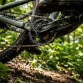 SRAM Kettenblatt X-Sync 2 SL Eagle 34T lunargrau am Mountainbike, schlammig auf einem Trail im Wald.