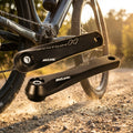 Schwarzes Miche Syntium H ISIS E-Bike Kurbel-Set (458g) schwebt über Schotterweg vor Rad.