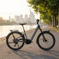 Komfortables Centurion Country R2000 L EP2 City- & Trekkingrad, marinegrau, am Flussufer mit Stadt-Skyline.