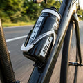 Elite Flaschenhalter Custom Race schwarz/weiß glanz mit Trinkflasche am Carbon-Rennrad auf sonniger Straße.