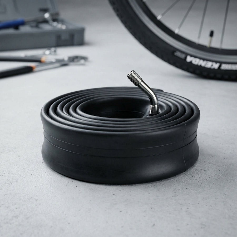 Kenda Fahrradschlauch Reha 10x2 (54-152) AV 45/45° Ventil auf Betonboden, im Hintergrund Fahrradreifen & Werkzeug.