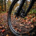 Voxom Scheibenbremsbeläge für Shimano XT am Mountainbike-Vorderrad auf schlammigem Herbstweg.