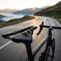 Schwarzer Prologo Dimension 143 CPC Tirox Sattel auf nassem Rennrad auf Bergpass bei Sonnenaufgang.