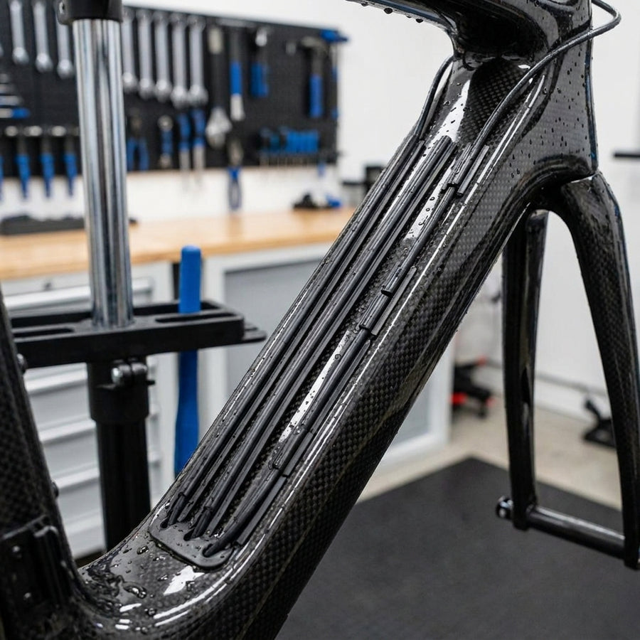 SHIMANO Kabelabdeckung schwarz für Di2 Kabelgehäuse am Carbon-Fahrradrahmen in der Werkstatt.