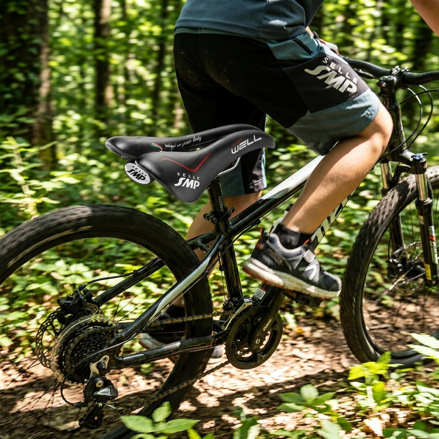 Schwarzer Selle SMP Junior Well Unisex-Sattel am Mountainbike auf Waldweg.