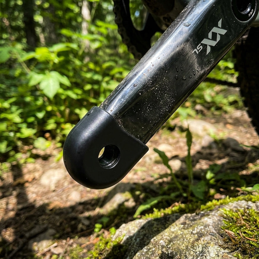 Schwarzer SRAM Kurbelarmschutz XX/XXSL an Fahrradkurbel auf einem Mountainbike-Trail.