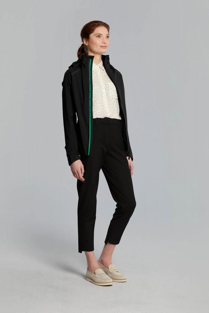 Frau trägt schwarze taillierte Basil Skane Damen Regenjacke mit grünem Reißverschluss, wasserdicht & atmungsaktiv.