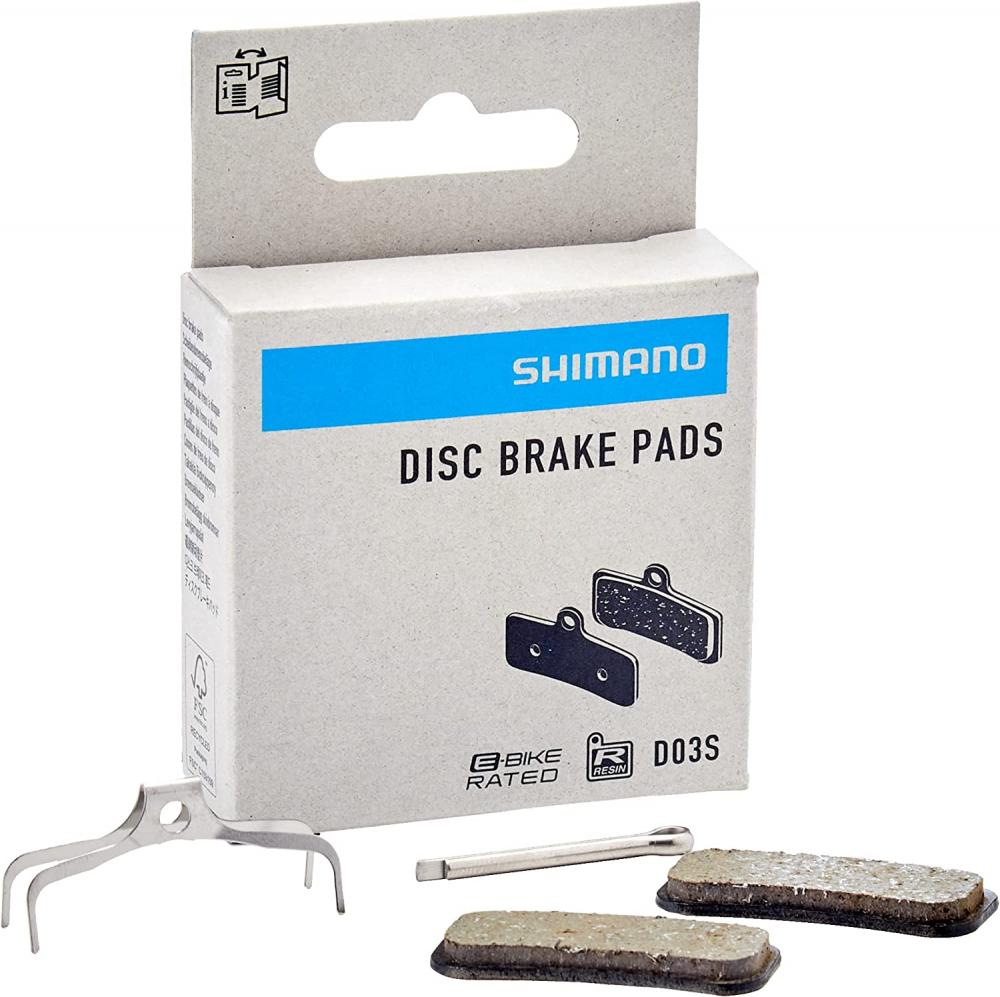 Shimano Scheibenbremsbelag D03S organisch. Produktbox mit zwei Bremsbelägen, Feder und Sicherungssplint.