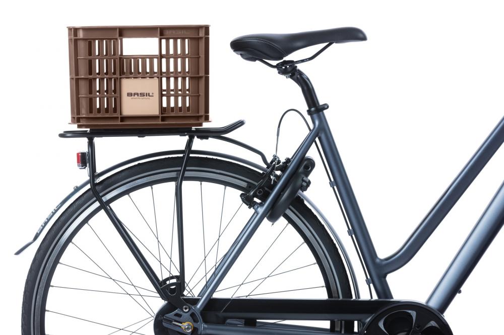 Braune BASIL Crate S Fahrradkiste (17,5 L) aus recyceltem Kunststoff auf dem Heckträger eines Fahrrads.