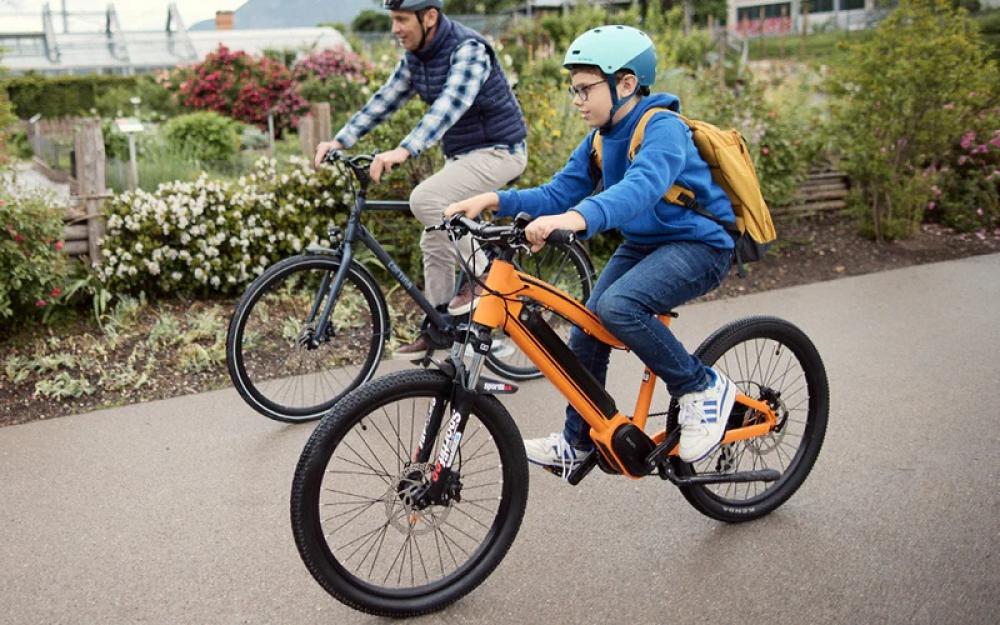 Kind fährt orangefarbenes Fahrrad mit bequemem Selle Royal Explora Junior M Kinderfahrradsattel.